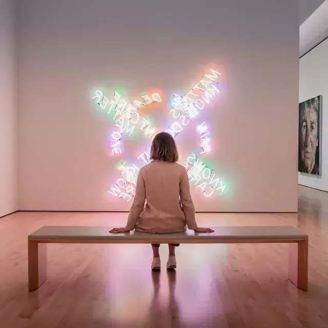 一个女人, 坐在长椅上, regarde une œuvre d’art lumineux contemporain au SF MOMA à 贝博体彩app.